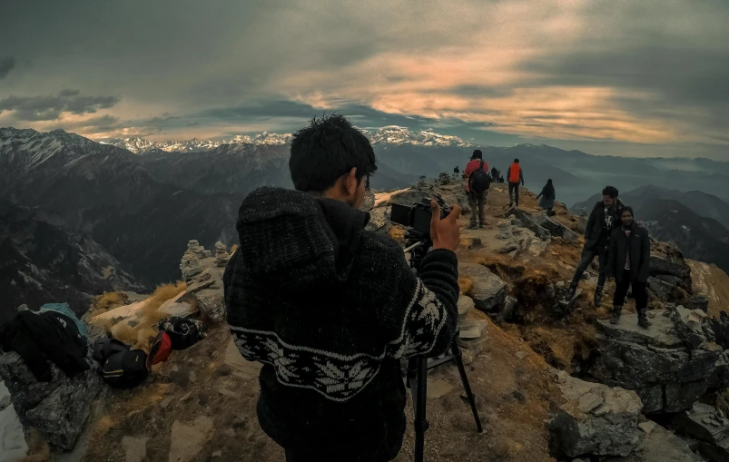 a group of people standing on top of a mountain, a picture, pexels contest winner, art photography, holding a camera, tripod, cinematic outfit photo, a photo of a man