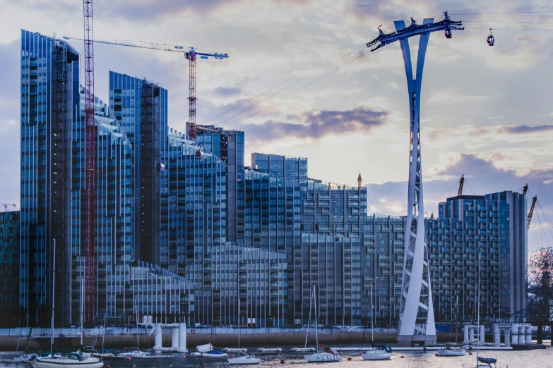 a group of boats sitting on top of a body of water, by Raphaël Collin, pexels contest winner, hypermodernism, tall bridge with city on top, cranes, renzo piano, post processed 4k