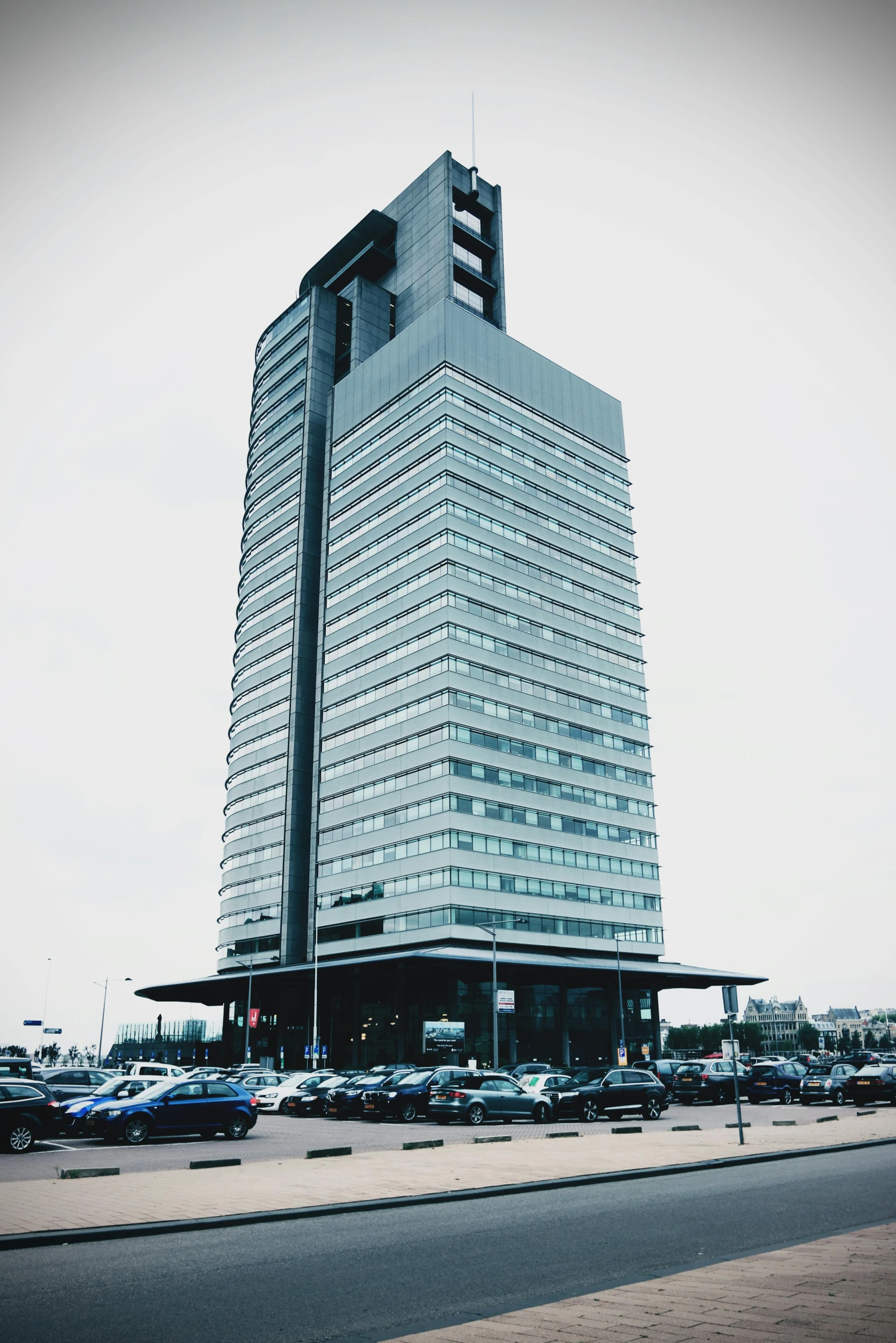 a tall building sitting on the side of a road, inspired by René Burri, unsplash, brutalism, capital of estonia, low quality photo, helipad, panorama