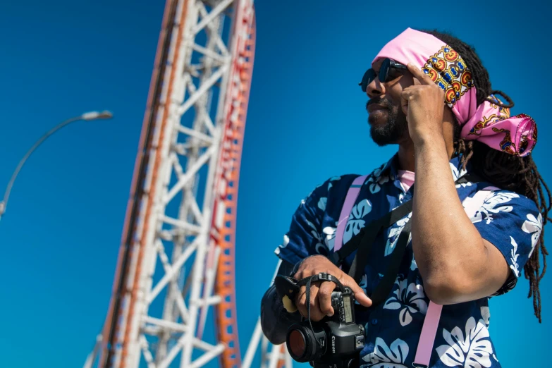 a man with a pink bandana talking on a cell phone, pexels contest winner, afrofuturism, roller coasters, posing for a picture, crane shot, oceanside