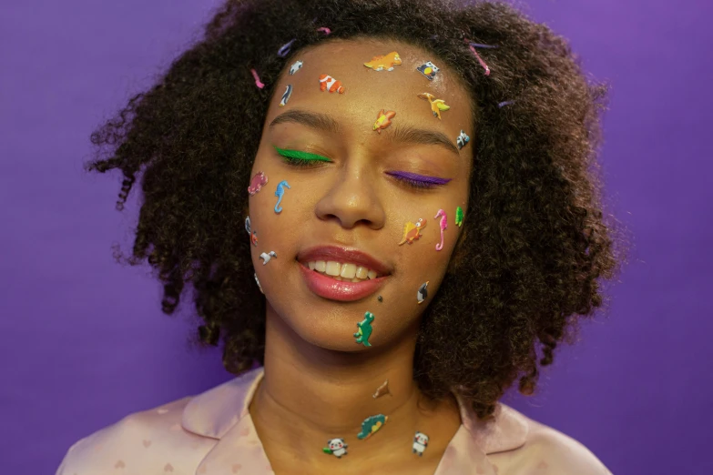 a woman with sprinkles on her face, an album cover, trending on pexels, purple skin color, puffy sticker, multicolored, earbuds jewelry
