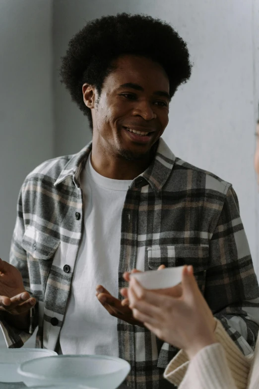 two people sitting at a table having a conversation, trending on pexels, happening, black teenage boy, with a white mug, man standing, on a gray background