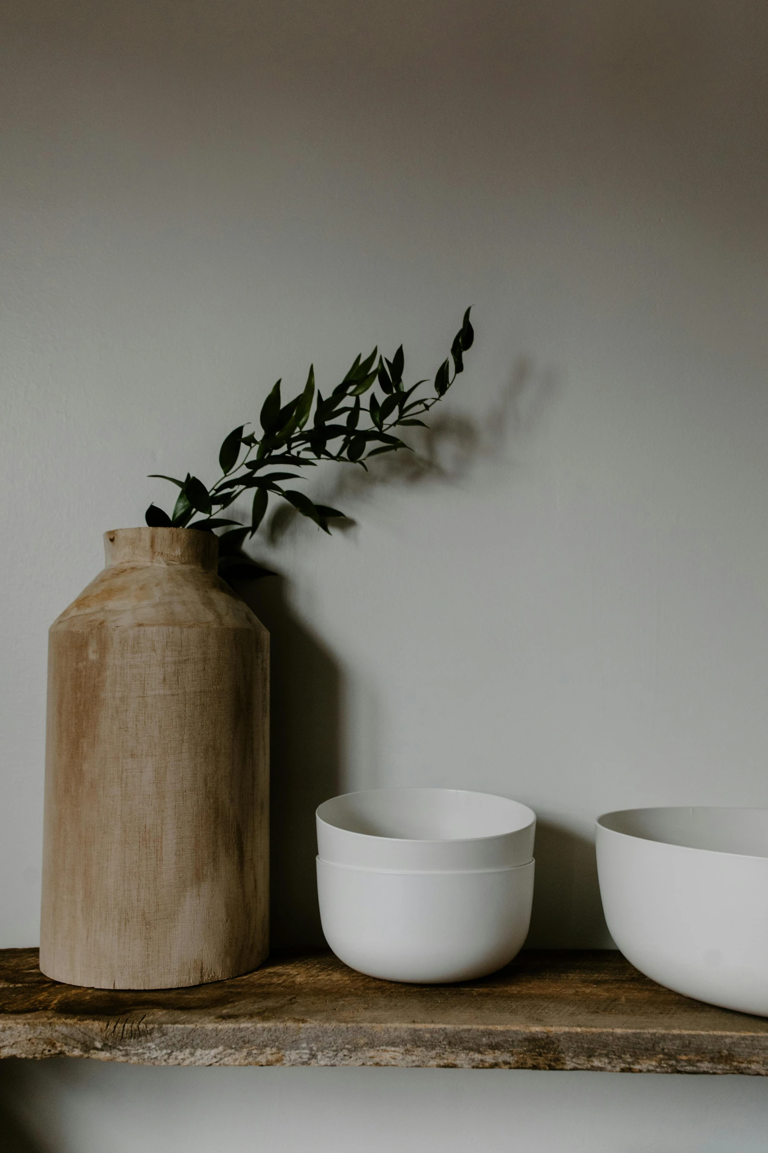 a couple of bowls sitting on top of a wooden shelf, a still life, trending on unsplash, minimalism, white vase, branches and foliage, large and tall, beautiful low light