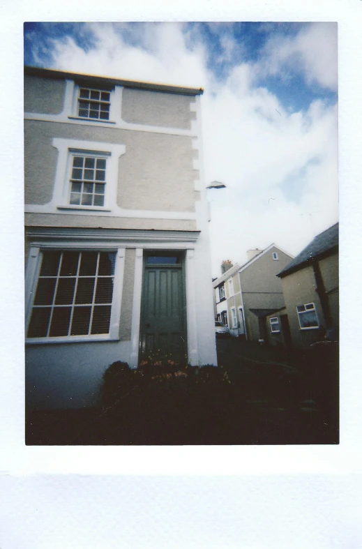 a polaroid picture of a white house with a green door, a polaroid photo, inspired by Rachel Whiteread, unsplash, maryport, low quality photo, view from the street, pinhole photo