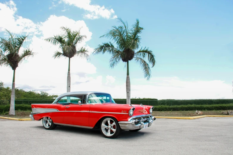 a red classic car parked in a parking lot, by Gavin Nolan, pexels contest winner, miami beach, 1957 chevrolet bel air, tropical style, skies behind