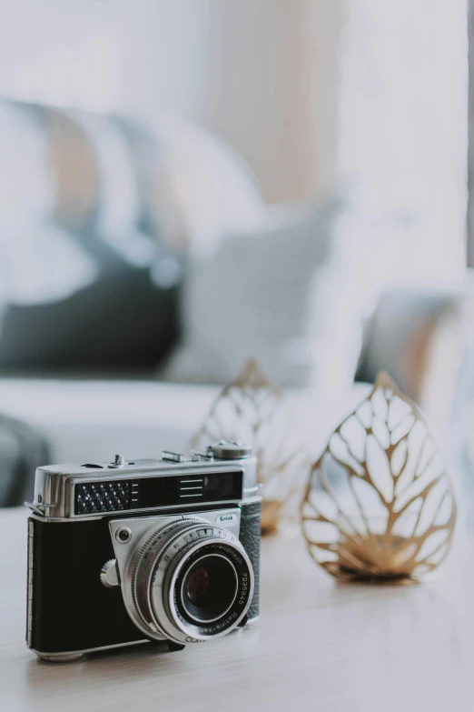 a camera sitting on top of a white table, by Tom Bonson, unsplash contest winner, decoration around the room, lavishly decorated, soft vintage glow, bokeh chrome accents