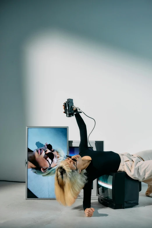 a woman doing a handstand in front of a television, inspired by Anna Füssli, video art, taking a selfie, lying down, qled, with a robotic arm