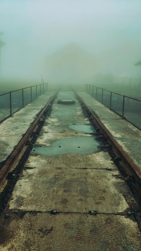 a train track on a foggy day, an album cover, inspired by Elsa Bleda, unsplash, abandoned structures, standing water, catwalk, snapchat photo