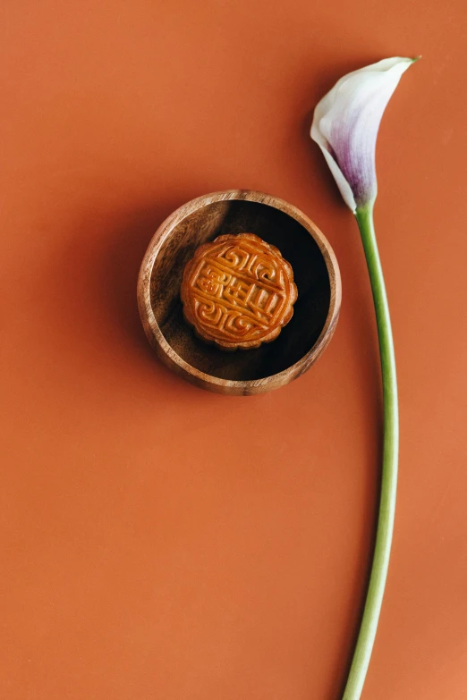 a white flower sitting on top of a wooden bowl, inspired by Luo Mu, trending on unsplash, art nouveau, pastry, orange, hong kong, petite