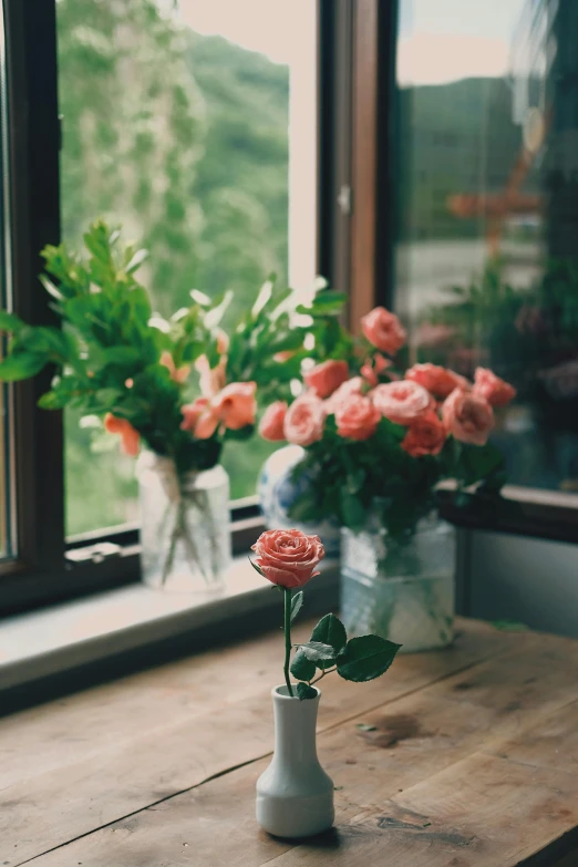 a vase of flowers sitting on top of a wooden table, unsplash contest winner, romanticism, roses and lush fern flowers, windowsill, pink rose, in shades of peach