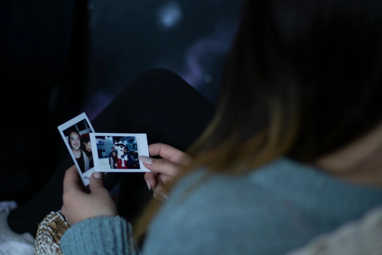 a woman sitting on top of a bed holding a polaroid, a polaroid photo, unsplash, holography, group of people in a dark room, holding a tiny galaxy, ariana grande photography, close-up photograph