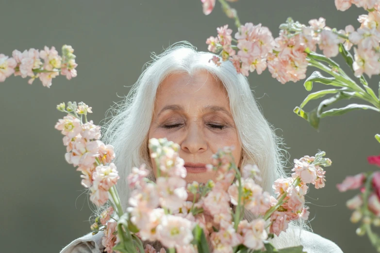 a woman standing in front of a bunch of flowers, trending on unsplash, hyperrealism, relaxed dwarf with white hair, fragrant plants, aging, eyes closed