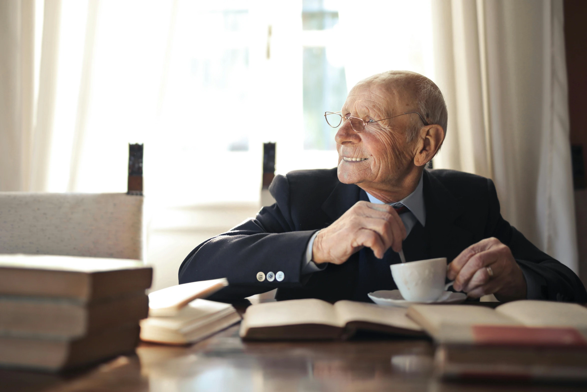 a man sitting at a table with a cup of coffee, an 80 year old man, multiple stories, scholar, thumbnail