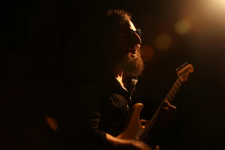 a man with a beard playing a guitar, profile image, glowing, michael pangrazio, dark. no text