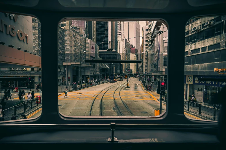 a train traveling down a city street next to tall buildings, unsplash contest winner, looking through a window frame, city like hong kong, tram, inside of a car