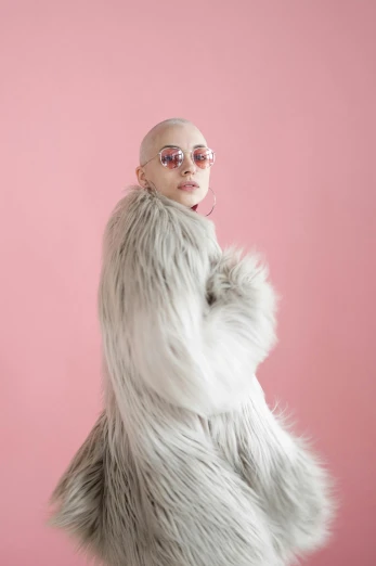 a woman in a fur coat on a pink background, an album cover, trending on pexels, antipodeans, shaved head, grey alien, full body! shot, pink glasses