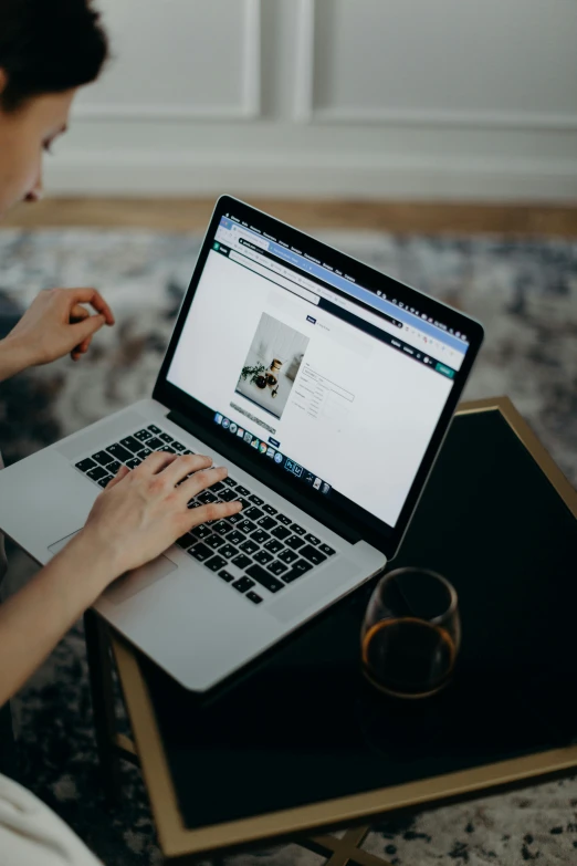 a woman sitting on a couch using a laptop computer, trending on unsplash, on a white table, with intricate details, thumbnail, evening time