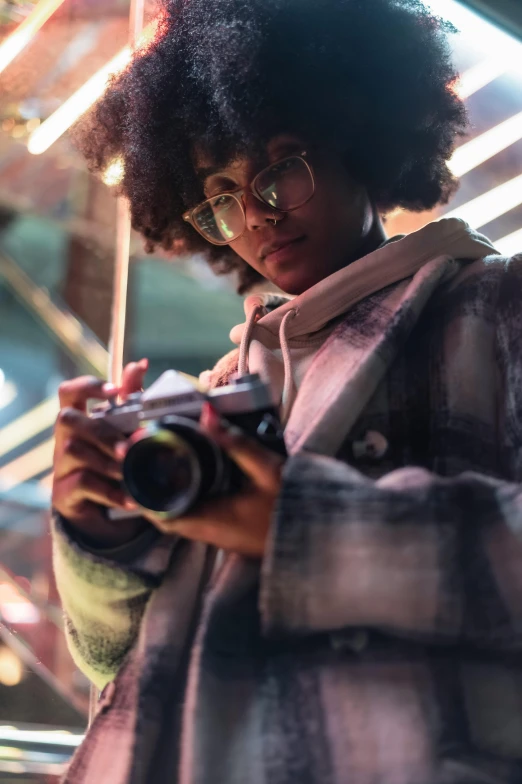 a woman taking a picture with a camera, a picture, inspired by Gordon Parks, trending on pexels, afrofuturism, girl wearing hoodie, girl with glasses, good lighted photo, with afro