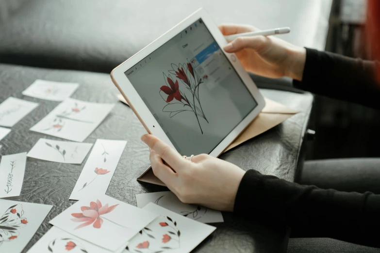 a person using a tablet computer on a table, a drawing, by Carey Morris, trending on pexels, japanese flower arrangements, card art, on a gray background, performing