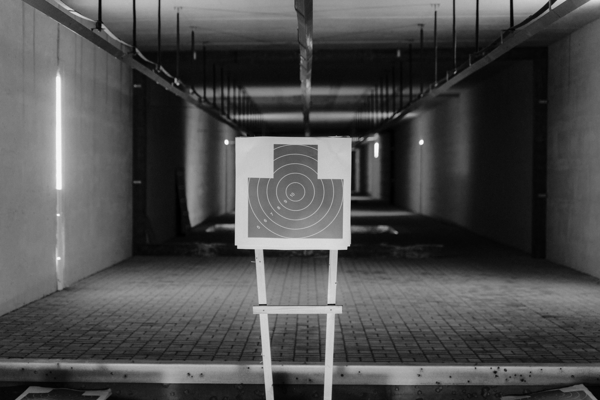 a black and white photo of a target in a building, small chamber. hyperrealistic, behaelterverfolgung, high-quality photo, pr shoot