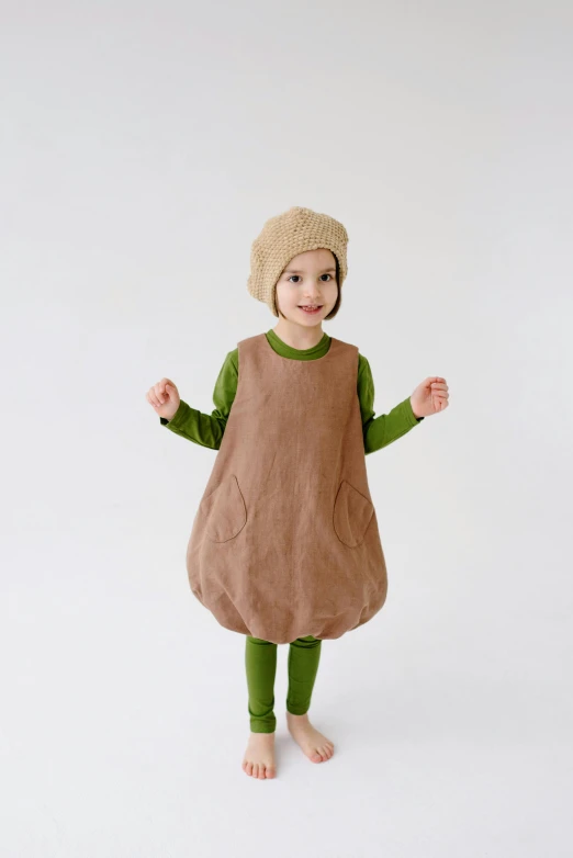 a little girl wearing a brown dress and a brown hat, an album cover, inspired by Elsa Beskow, pexels, an avocado chair, full - body - front - shot, けもの, costume desig