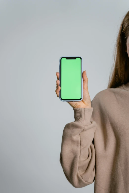 a woman holding up a phone with a green screen, hypermodernism, muted colors with minimalism, 1 4 9 3, android phones, highly symmetrical