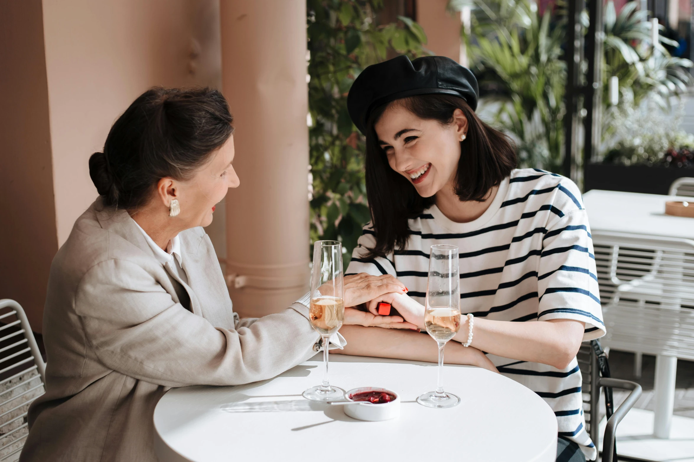 two women sitting at a table with wine glasses, pexels contest winner, wearing a french beret, sleek hands, family friendly, gushy gills and blush