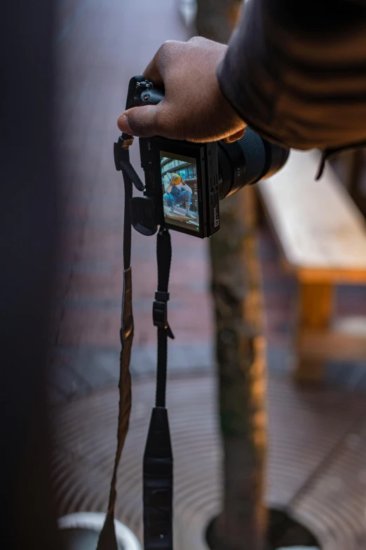 a person taking a picture with a camera, inspired by Steve McCurry, rugged details, hanging, sony a 6 3 0 0, high - angle