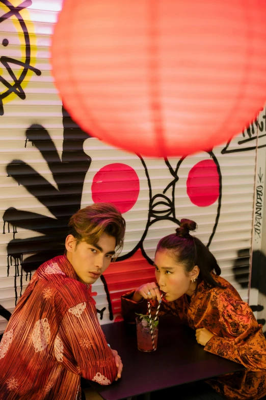 a couple of women sitting at a table, inspired by Taro Yamamoto, trending on pexels, graffiti, handsome japanese demon boy, chinese lanterns, backdrop, looking serious