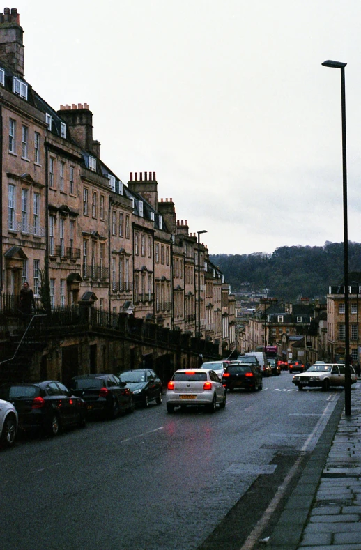 a street filled with lots of traffic next to tall buildings, inspired by Thomas Struth, renaissance, bath, city on a hillside, neo classical architecture, wet street