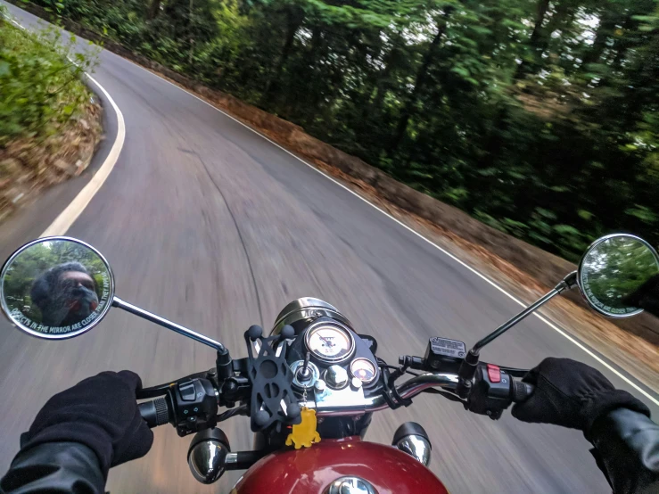 a person riding a motorcycle down a curvy road, unsplash, photorealism, assamese aesthetic, cockpit view, triumph, camera angle from below