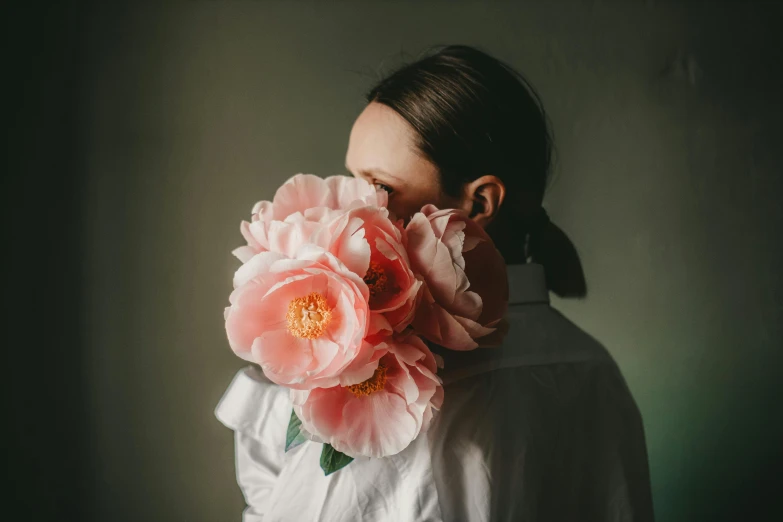 a woman holding a large pink flower in front of her face, by Rebecca Horn, peony flowers, sydney hanson, lightly dressed, photograph taken in 2 0 2 0