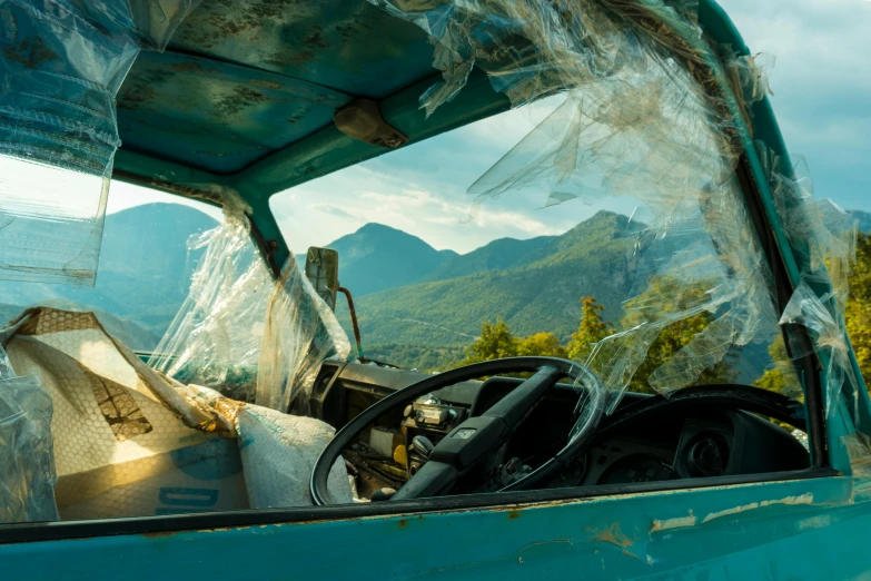 a car covered in plastic sitting on the side of a road, inspired by Elsa Bleda, pexels contest winner, hyperrealism, destroyed mountains, sri lankan landscape, looking out window, teal aesthetic