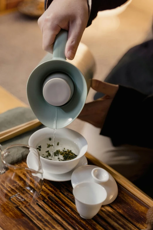 a person pouring tea into a cup on a table, inspired by Gu An, mint, thumbnail, up close, porcelain organic