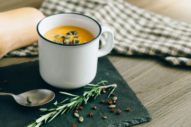 a close up of a cup of soup on a table, a still life, inspired by Charles Le Roux, unsplash, pumpkin, square, slate, white