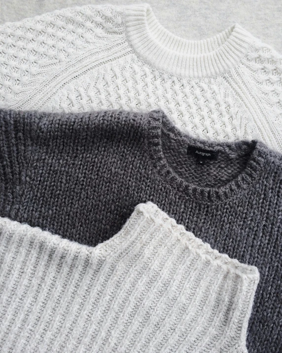a pile of sweaters sitting on top of each other, a stipple, unsplash, white and grey, three, wearing sweater, loosely cropped