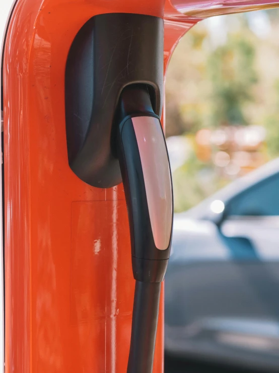 a close up of a charging station with a car in the background, by Randall Schmit, unsplash, happening, red and orange colored, instagram story, square, close up shot from the side