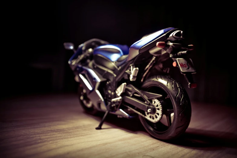 a close up of a motorcycle on a wooden floor, a tilt shift photo, by Adam Marczyński, photorealism, blue, night time, toy photo, realistic 3d model