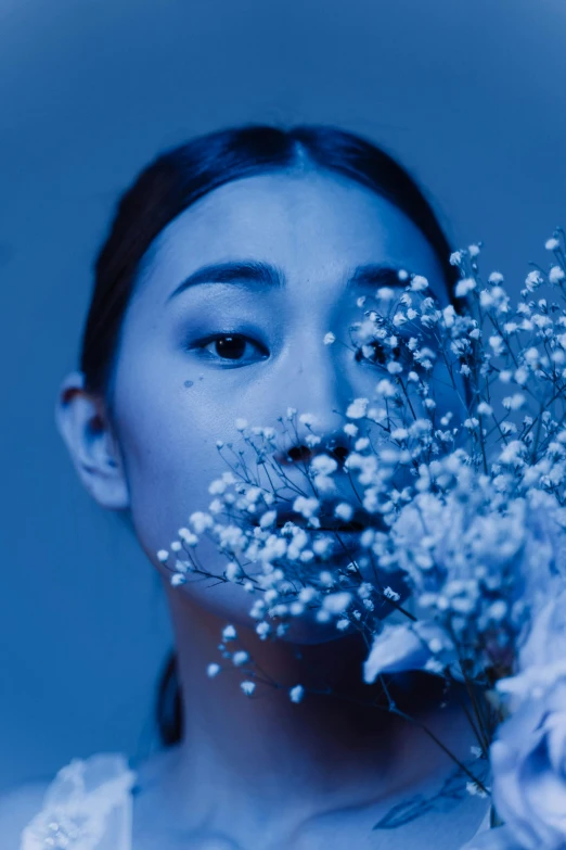 a woman holding a bouquet of flowers in front of her face, an album cover, inspired by Elsa Bleda, trending on unsplash, aestheticism, blue monochromatic, jingna zhang, portrait of ariana grande, young asian woman