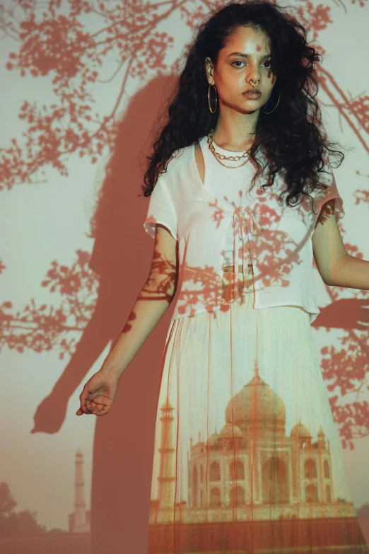 a woman that is standing in front of a wall, an album cover, arabesque, hindu aesthetic, under the soft shadow of a tree, long dark curly hair, backlighting