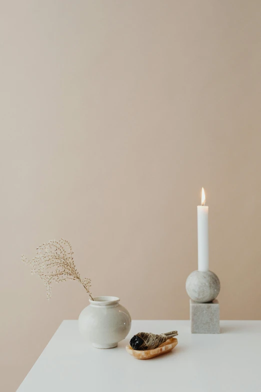 a white table topped with a vase and a candle, trending on pexels, minimalism, modern studio light soft colour, limestone, kailee mandel, light scatter