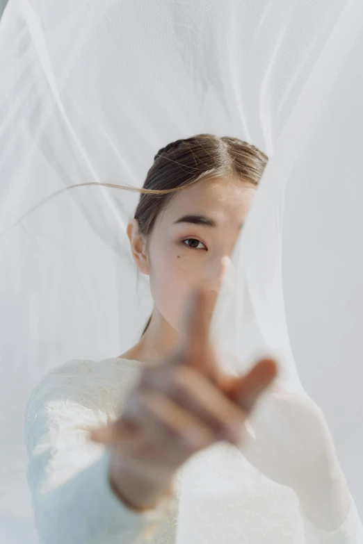 a woman with a veil covering her face, an album cover, inspired by Yu Zhiding, unsplash, hand gesture, pokimane, wearing a wedding dress, ad image