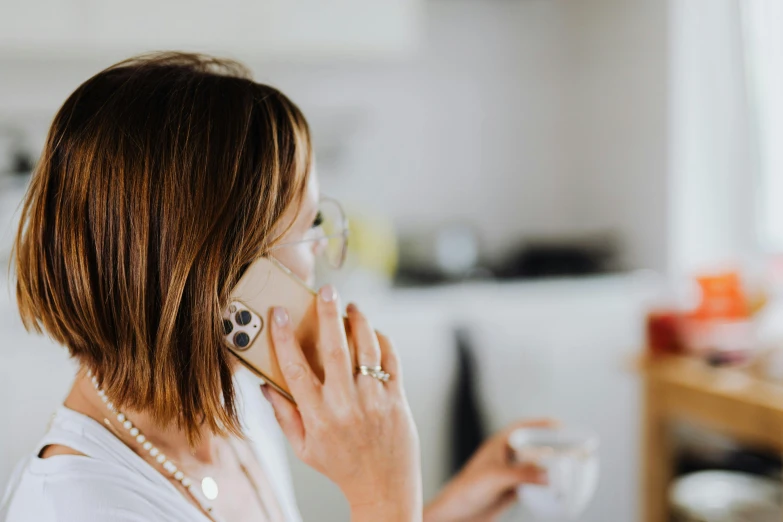 a woman talking on a cell phone while holding a cup, trending on pexels, ivory and copper, domestic, background image, profile image