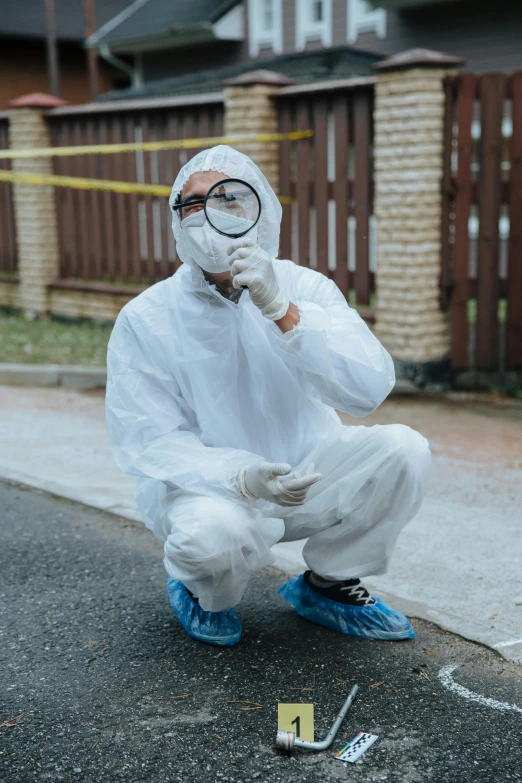 a man in a white hazmat suit holding a magnifying glass, outside on the ground, wearing gloves, viral post, serious