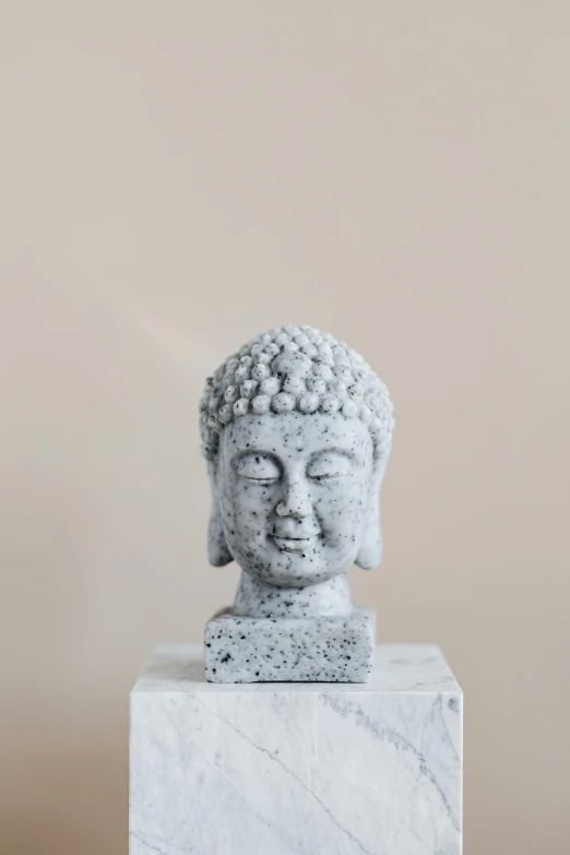 a buddha statue sitting on top of a marble block, a marble sculpture, inspired by Kim Tschang Yeul, trending on pexels, concrete art, detailed head, a frontal portrait of a delicate, singularity sculpted �ー etsy, small crown