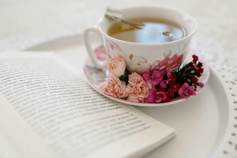 a cup of tea and a book on a table, flower power, promo image, multiple stories, close - up portrait shot