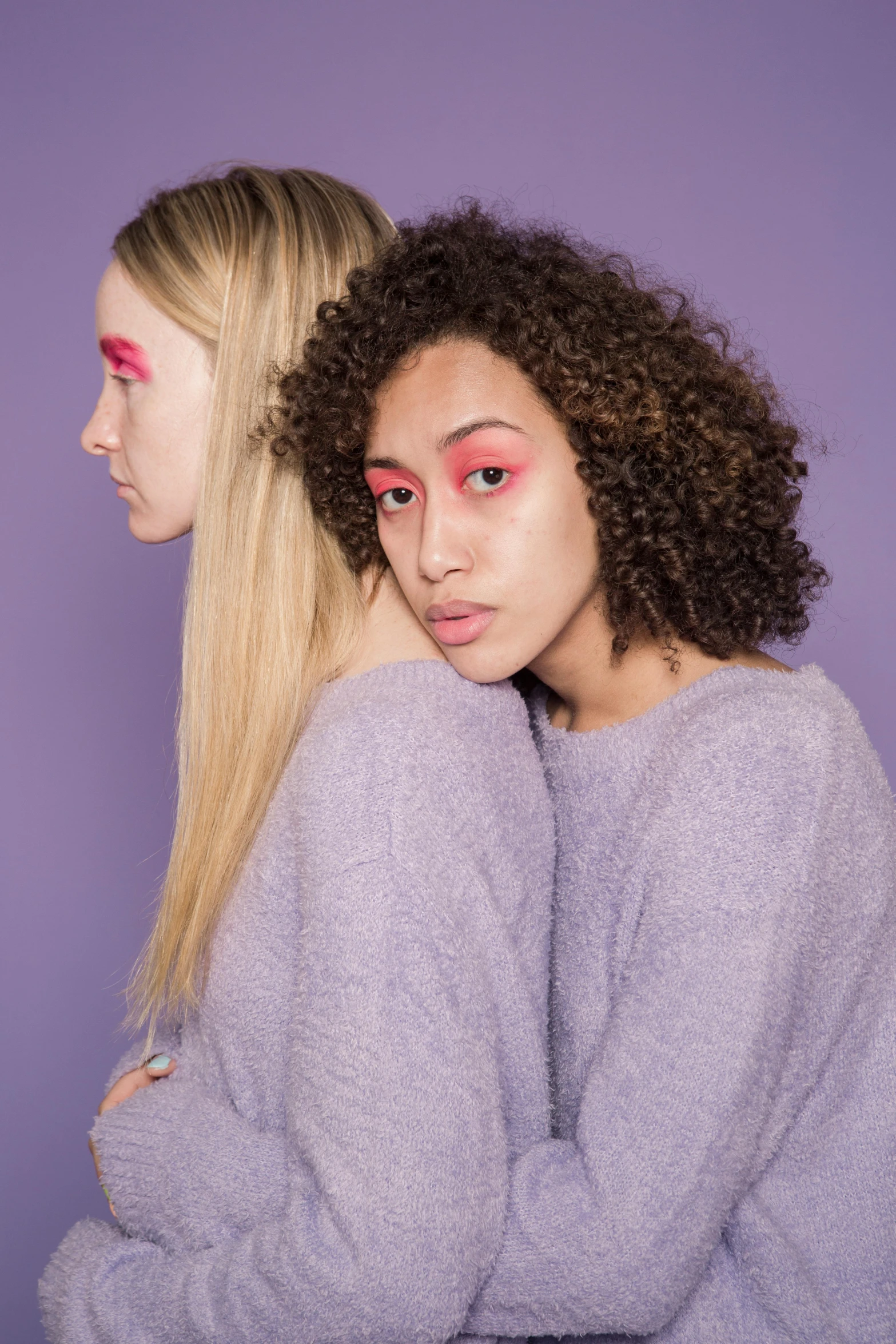 a couple of women standing next to each other, inspired by Maud Naftel, trending on pexels, aestheticism, purple skin, pastel makeup, clumps of hair, mixed race