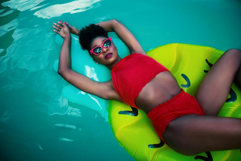 a woman laying on an inflatable raft in a pool, pexels contest winner, afrofuturism, green bright red, girl wearing round glasses, maria borges, waist high