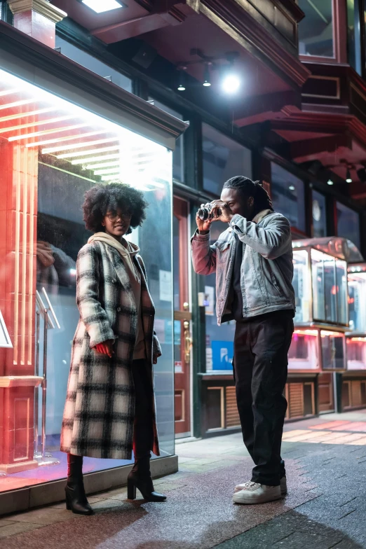 a couple of people standing in front of a store, pexels contest winner, cinematic outdoor lighting, jamel shabazz, behind the scenes photo, ( ( theatrical ) )