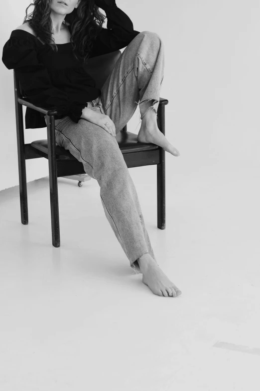 a black and white photo of a woman sitting in a chair, unsplash, realism, baggy jeans, shin jeongho, bare foot, (aesthetics)